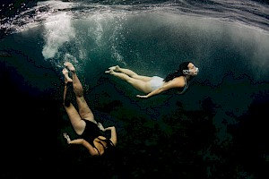 This colour photo shows models diving into the sea by James Bowden, UK  photographer, represented by Horton-Stephens photographer’s agents specialises in natural and authentic  lifestyle outdoors nature photographic images.