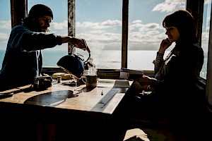ames Bowden, UK  photographer, represented by Horton-Stephens photographer’s agents specialises in natural and authentic  lifestyle outdoors nature photographic images, this colour photo shows a candid moment over coffee by the sea and landscape