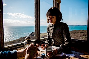 ames Bowden, UK  photographer, represented by Horton-Stephens photographer’s agents specialises in natural and authentic  lifestyle outdoors nature photographic images, this colour photo a lady drinking coffee by the sea